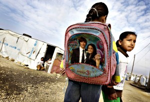 Syrian displaced children, wait outside their tent the school bu